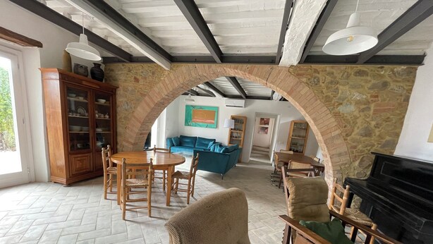 Amplia sala de estar con un arco de piedra, mobiliario de madera, chimenea y comedor.