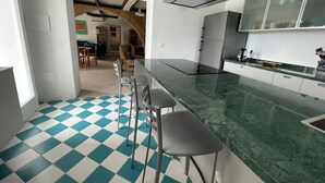 Una cocina moderna con piso a cuadros, una barra con taburetes y vista a un comedor.