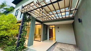 A modern building with a covered outdoor area, a tiled entrance, and a number sign. - One Roma by Cubes (Lusaka)