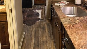 A kitchen with a granite countertop, stainless steel sink, and wooden cabinets.