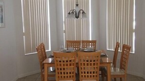 A dining area with a table set for four, surrounded by wooden chairs, and a chandelier hanging above. - Calabay Parc - Spacious 4 bed to suit your family vacation (Davenport)