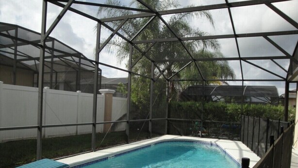 A rectangular pool with a white deck and blue-striped lounge chairs. - Calabay Parc - Spacious 4 bed to suit your family vacation (Davenport)