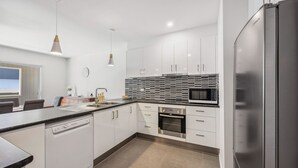 A modern kitchen with white cabinetry, a built-in oven, a microwave, and a dishwasher. - Stratton Summit 2, 5 bedroom townhouse in Jindabyne. (Jindabyne)