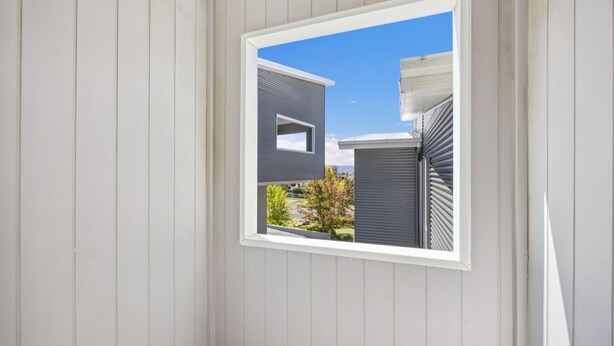 A window with a view of a modern house and a garden. - Stratton Summit 2, 5 bedroom townhouse in Jindabyne. (Jindabyne)