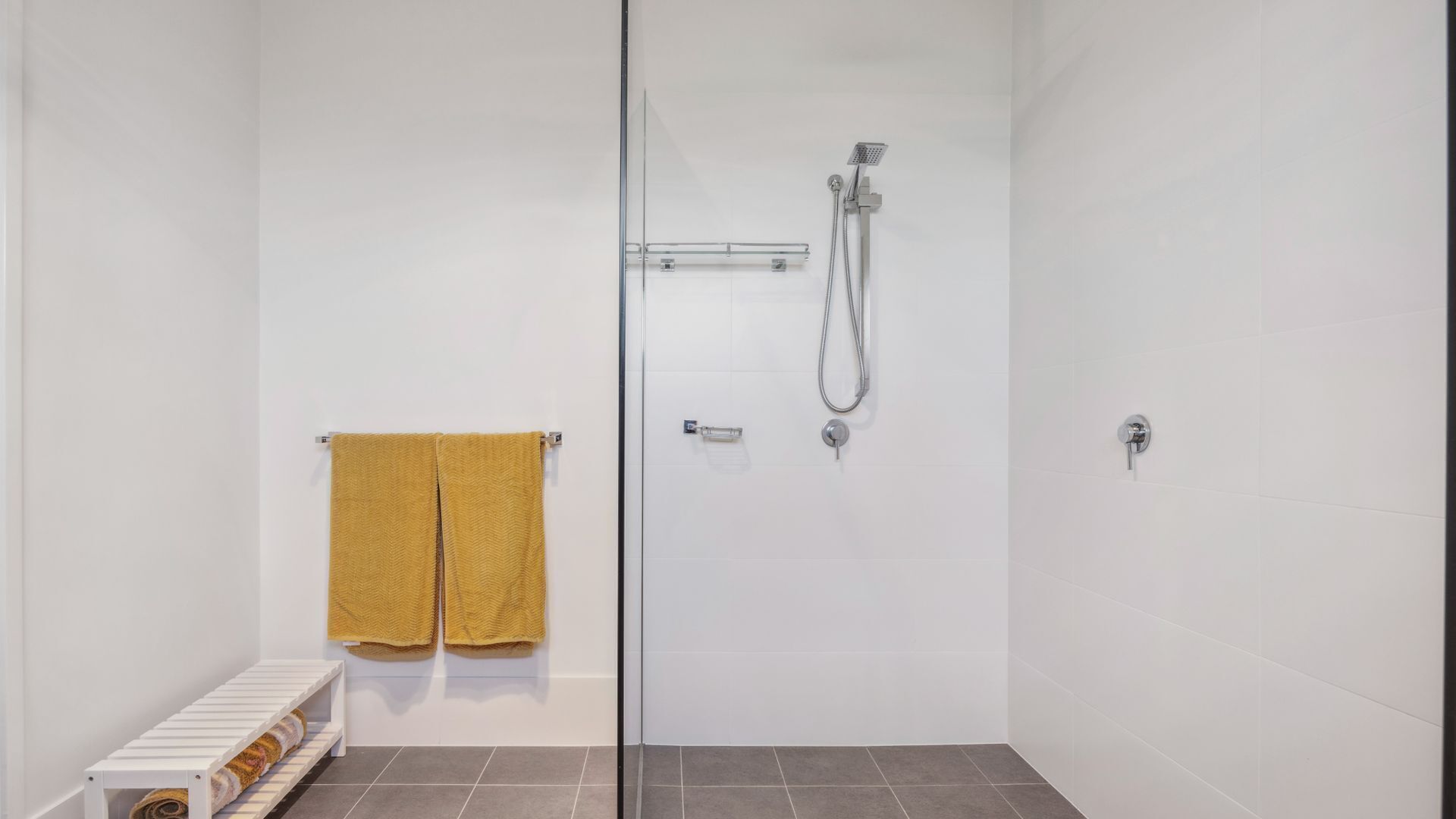 Un espace douche clos par des parois de verre, équipé d’un pommeau de douche à main et d’un robinet mural.