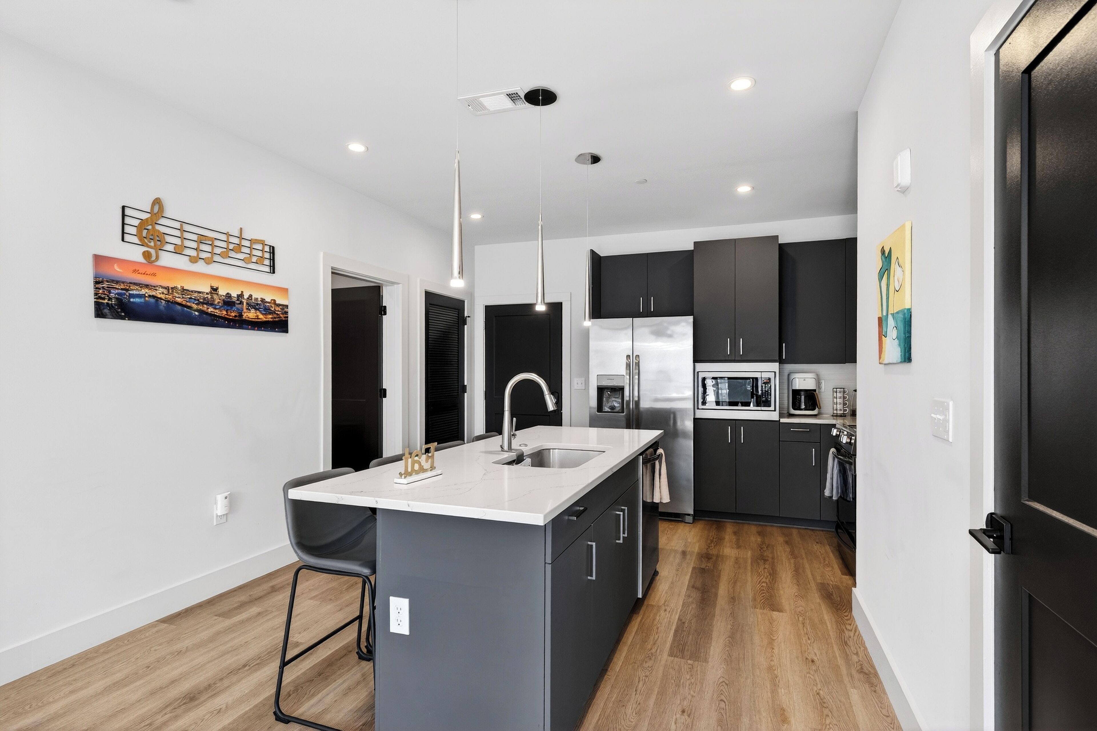 A modern kitchen with a central island, dark cabinets, and stainless steel appliances.