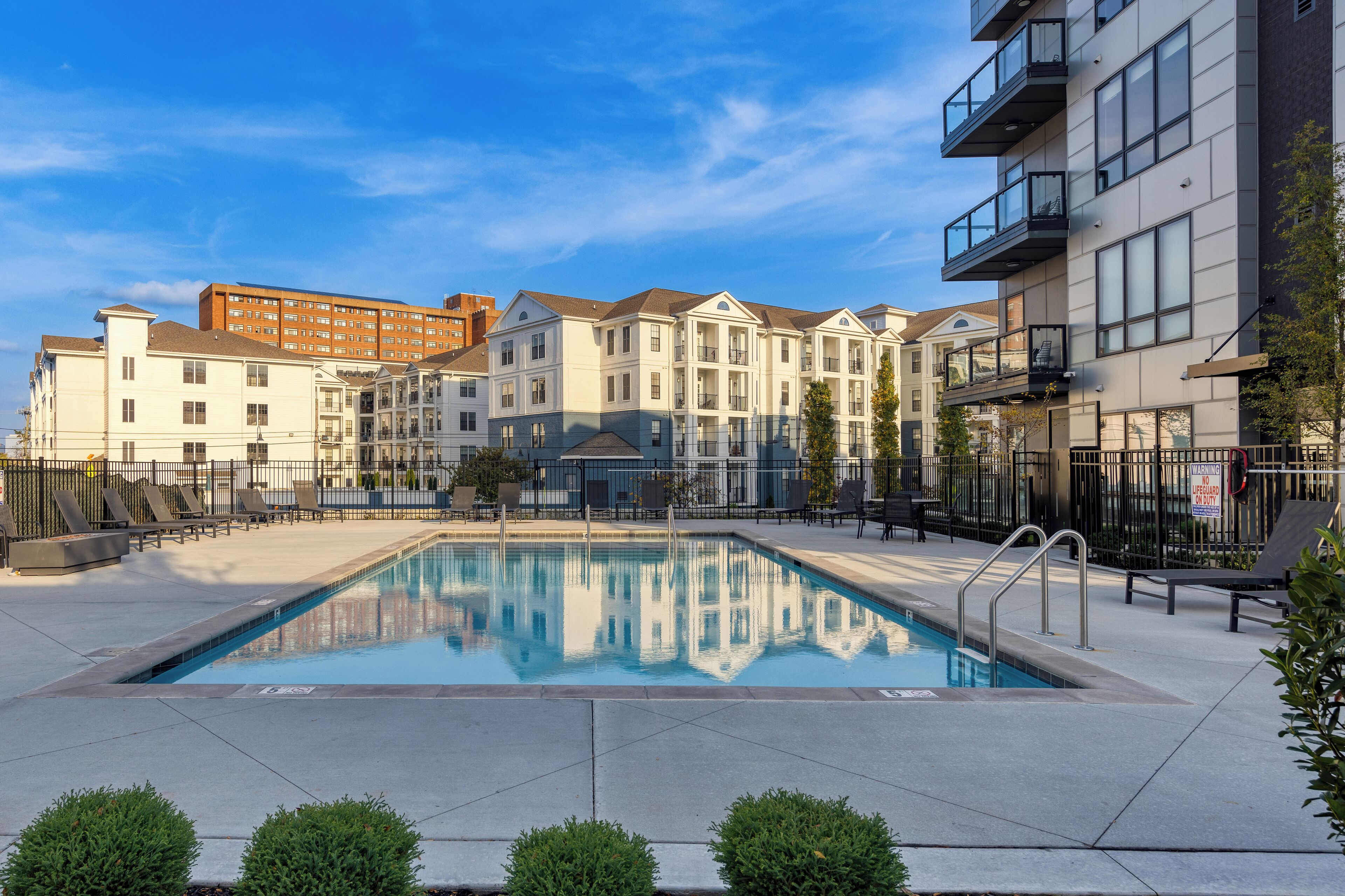 A swimming pool surrounded by modern buildings, with a clear sky above.