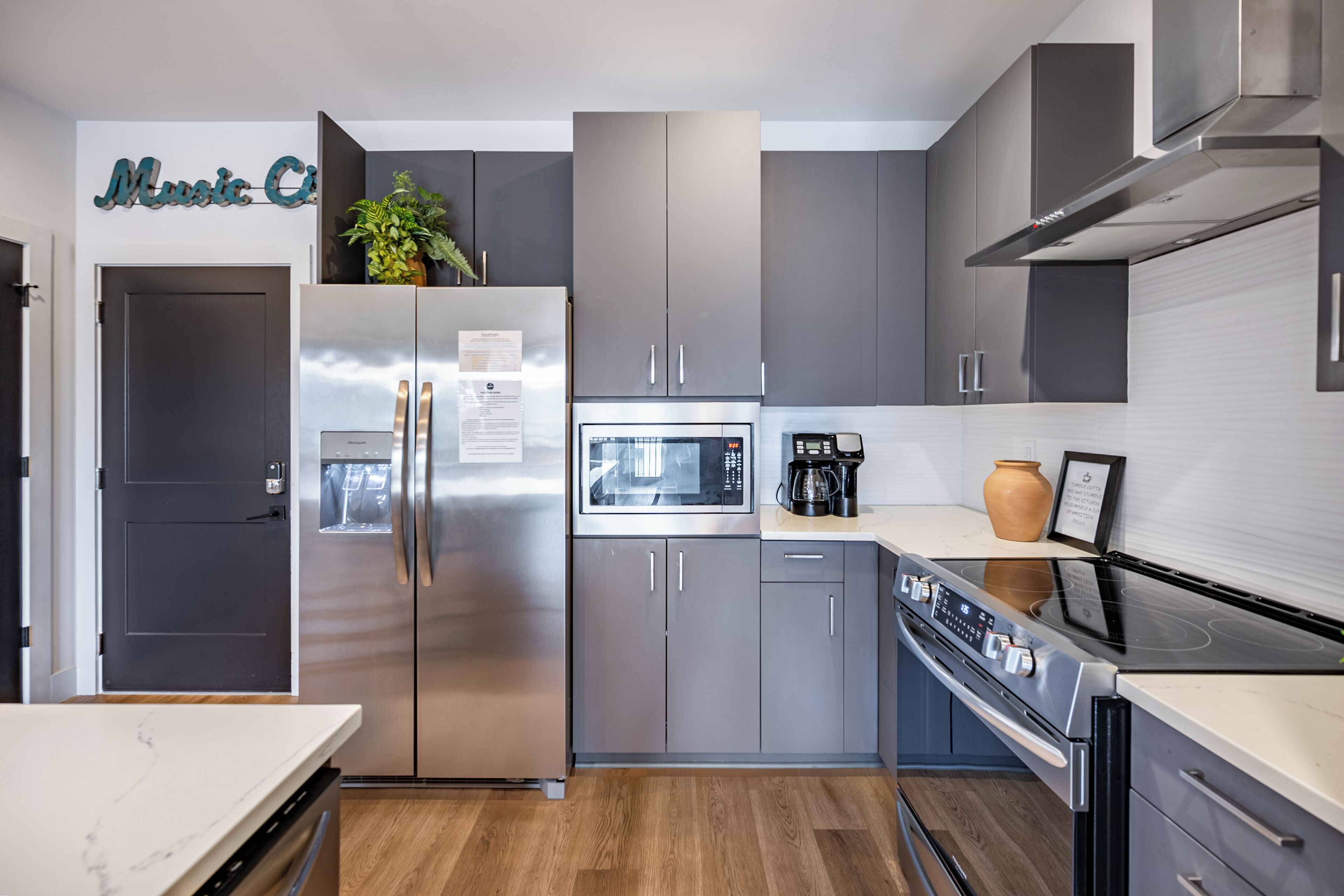 Una cocina moderna con electrodomésticos de acero inoxidable, gabinetes grises y encimera de mármol.