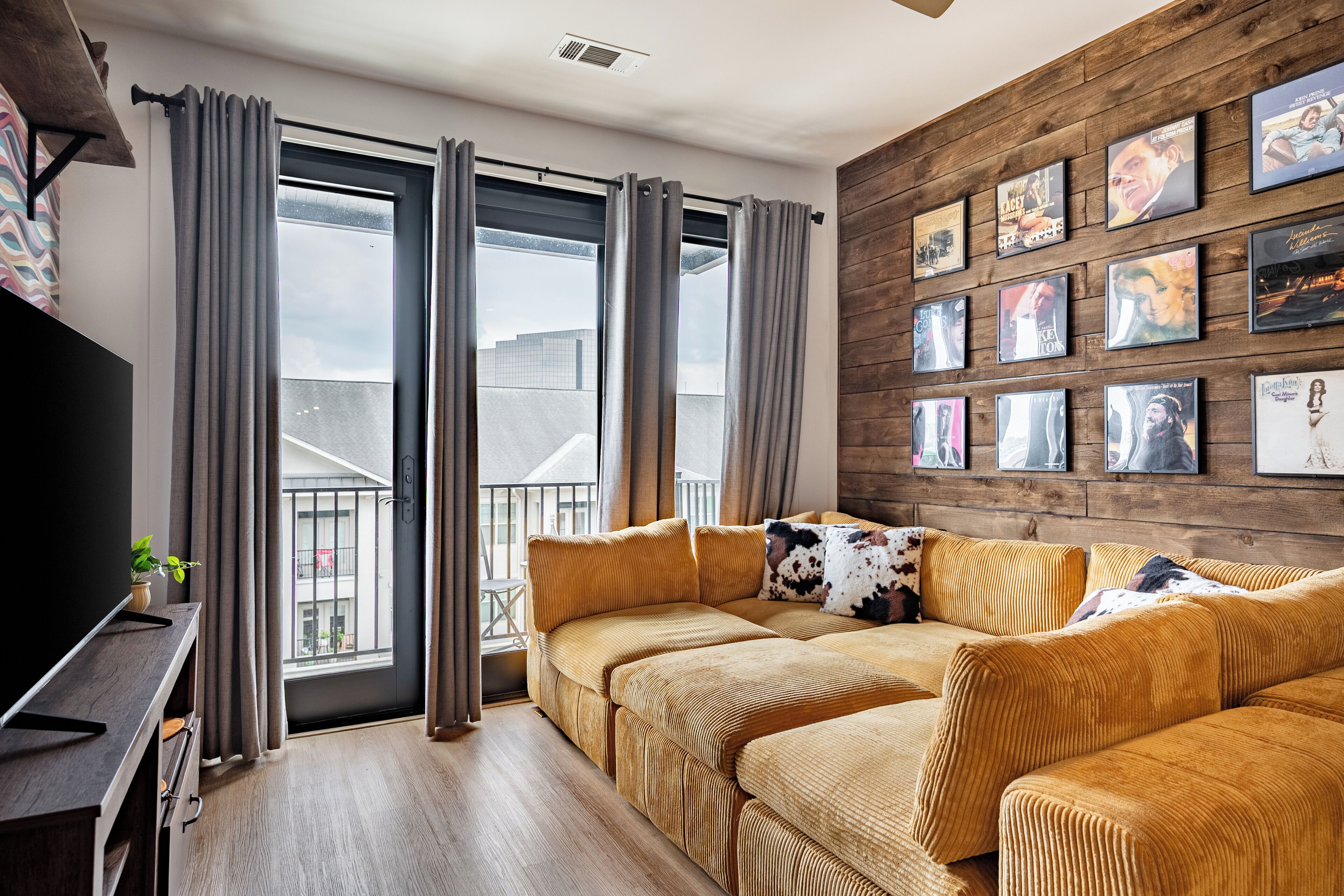 A modern living room with a sofa set, a TV, and a wall with framed pictures.