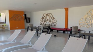A waiting area with lounge chairs, a wall with a decorative leaf pattern, and a bench with red cushions.