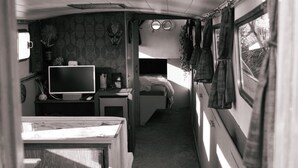 A compact RV interior with a kitchenette, a bed, and a TV. - Unique nature experience on the water, Bed in boat Jisperveld (Spijkerboor)