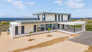 A modern two-story house with a flat roof, large windows, and a view of the sea. - Kas di Sol Infinito, NEW! Luxury Ocean View Villa w/ Huge Private Pool, 3 Bedrooms & Dive Facilities (Kralendijk)