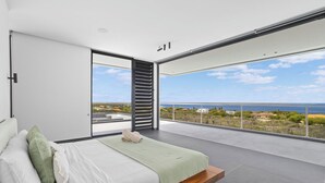 A modern bedroom with a large bed, a view of the sea, and a balcony. - Kas di Sol Infinito, NEW! Luxury Ocean View Villa w/ Huge Private Pool, 3 Bedrooms & Dive Facilities (Kralendijk)