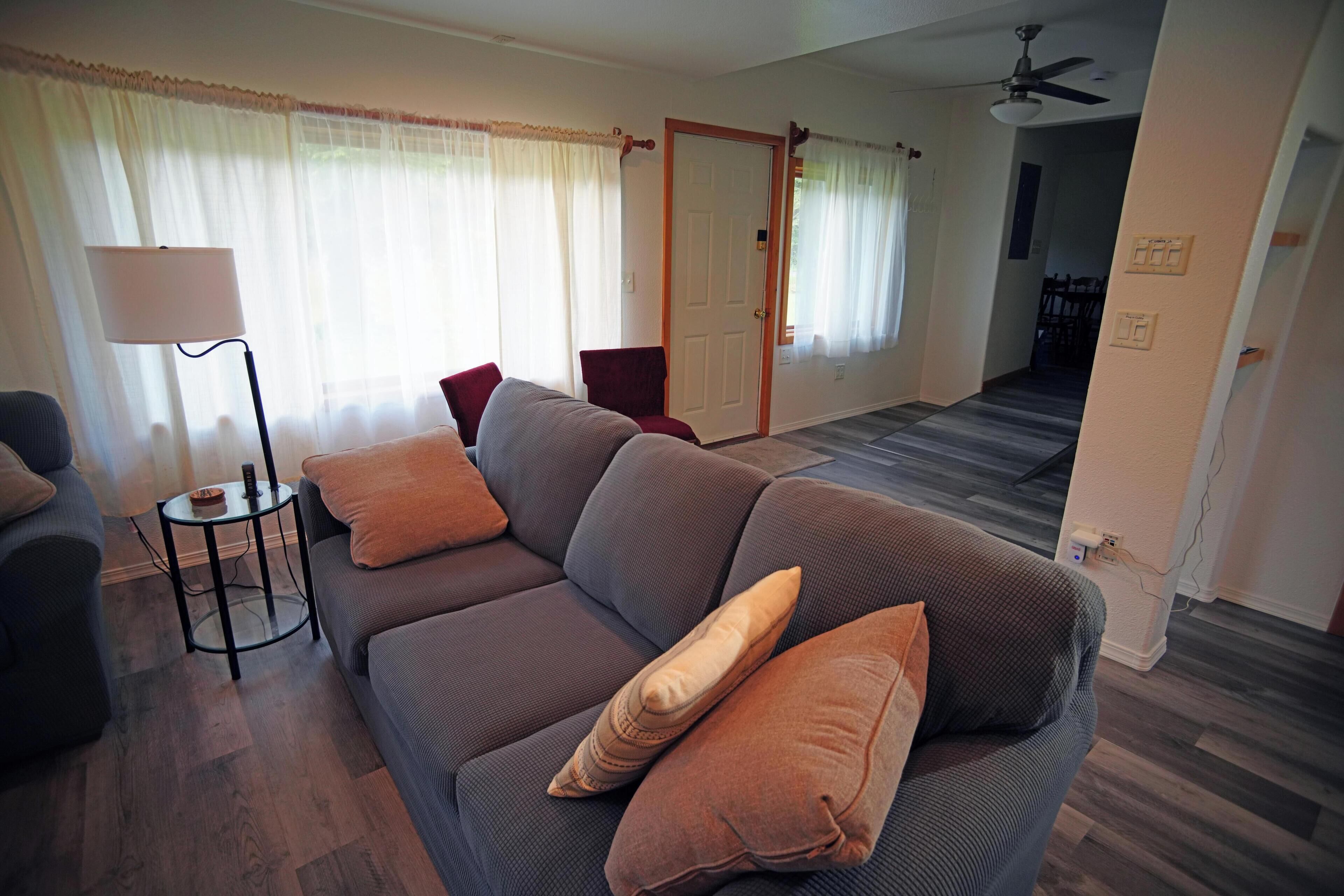 A living room with a sofa, a lamp, and a door leading to another room.