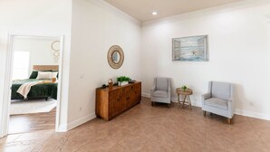 A spacious room with a wooden cabinet, two armchairs, a small round table, and a painting on the wall.