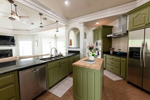 A kitchen with green cabinets, stainless steel appliances, and a center island with a vase.