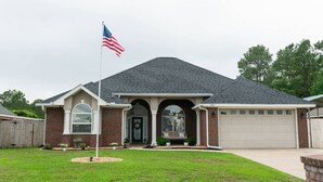 A single-story house with a front porch, a garage, and a flagpole with an American flag.