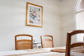 Un comedor con dos sillas de madera, una mesa con un mantel individual y un cuadro en la pared.
