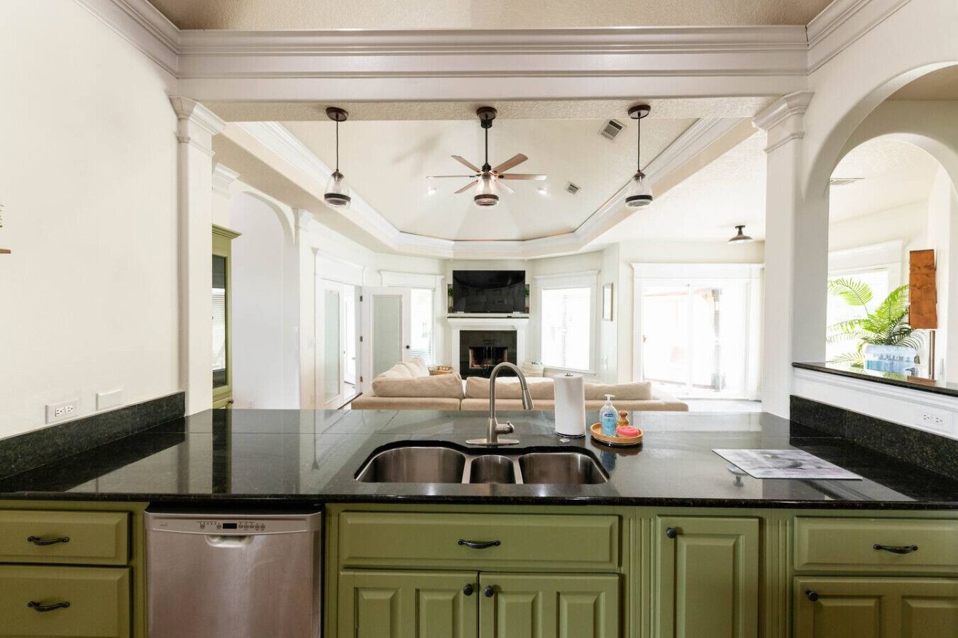 A kitchen with a central island, a dishwasher, and green cabinets.