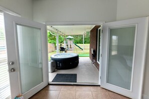 A covered patio area with a hot tub, a children's play structure, and a brick wall.