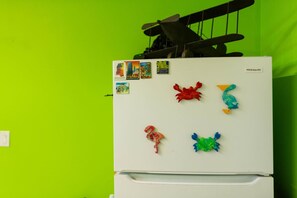 Un refrigerador blanco con imanes sobre una pared verde.