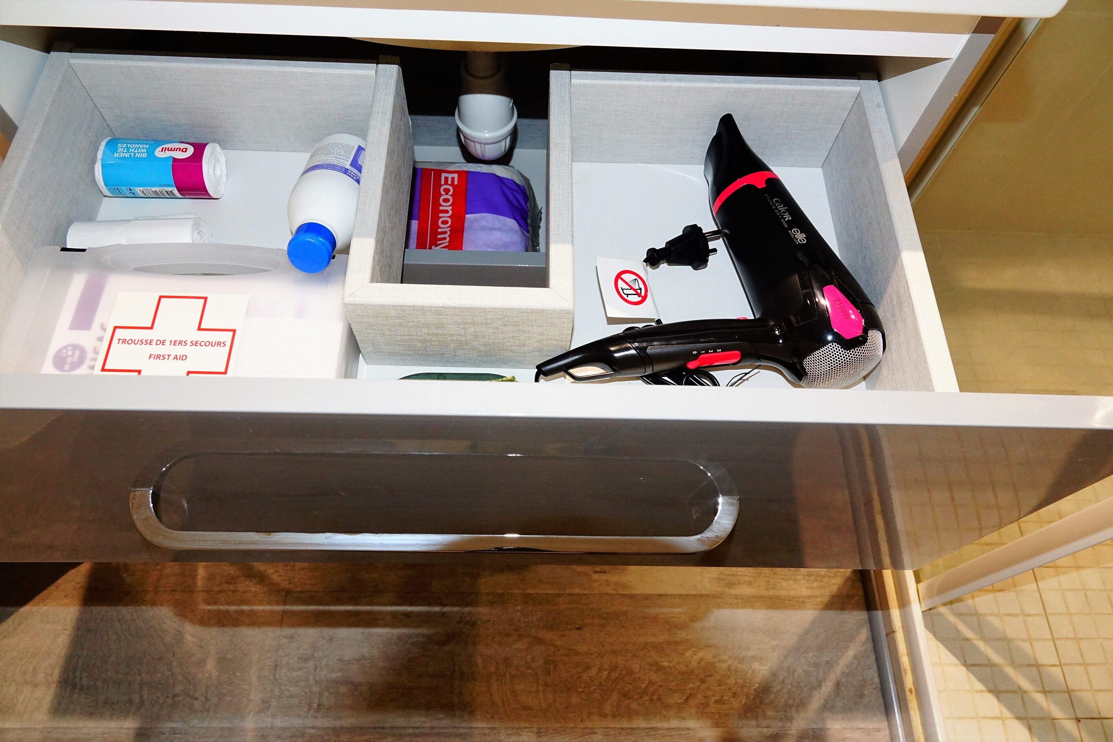 A drawer with a first aid kit, a hairdryer, and a box labeled 'Economy.'