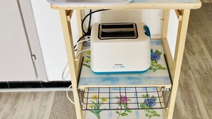 A kitchen counter with a coffee maker, toaster, and a tray with food items.