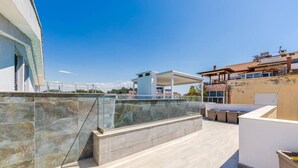Terrassa al terrat amb mur de pedra, zona d'seients coberta i vista a la ciutat.