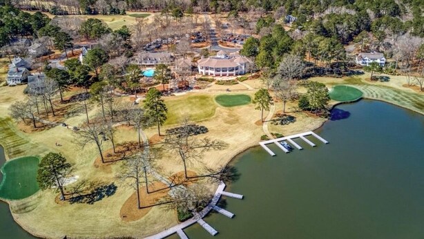 Luchtbeeld van een landgoed aan een meer, met een golfbaan, een groot huis en een steiger.