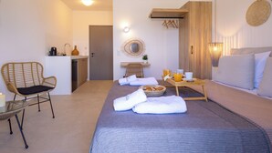 A modern hotel room with a bed, a sitting area with a chair, a small kitchenette, and a bathroom. - Cezaria Naxos Hotel (Naxos)