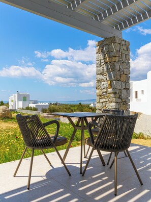 Une terrasse extérieure avec un pilier en pierre, deux chaises en osier et une table.