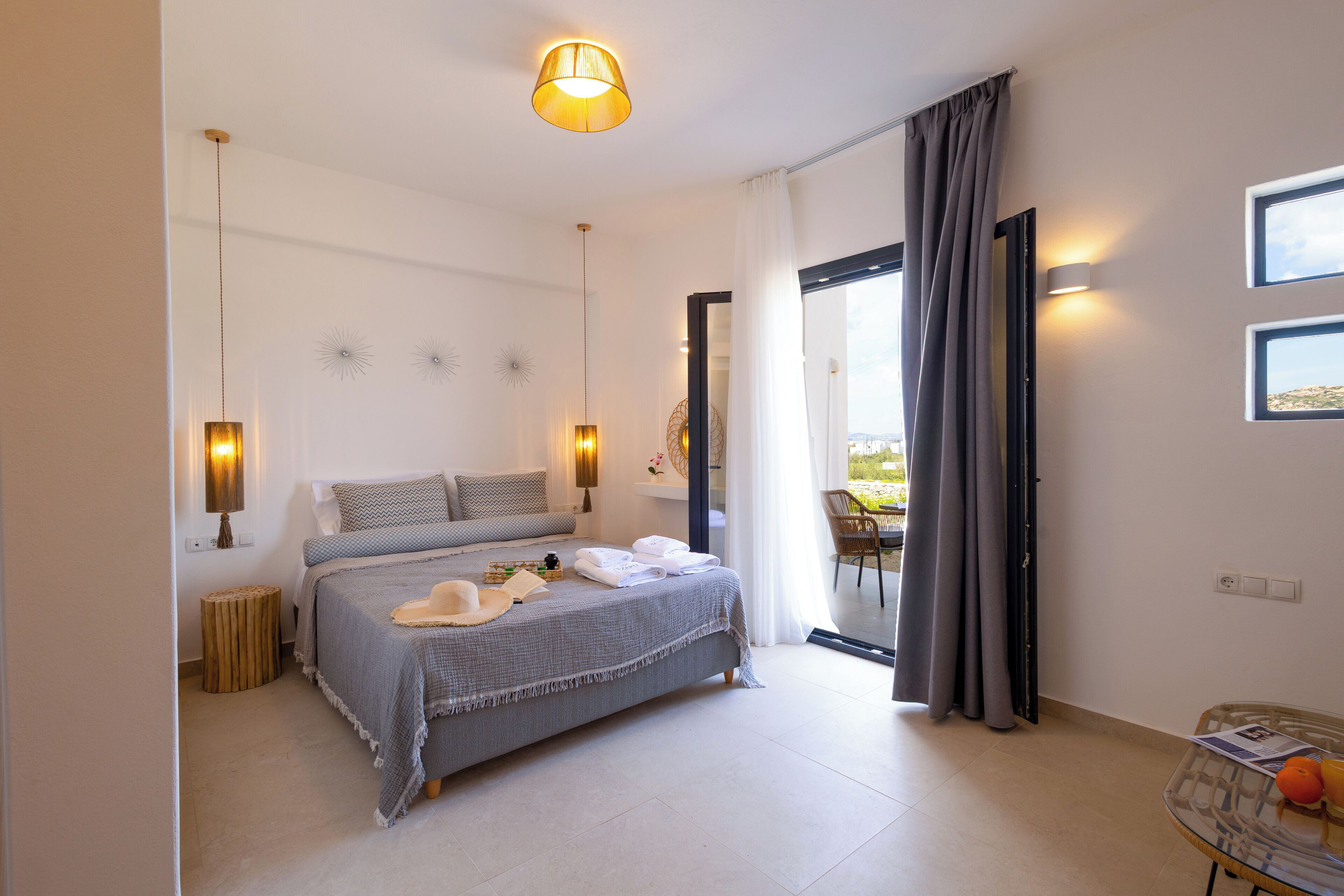 Un dormitorio con cama, lámparas de noche, una mesita redonda y una silla.