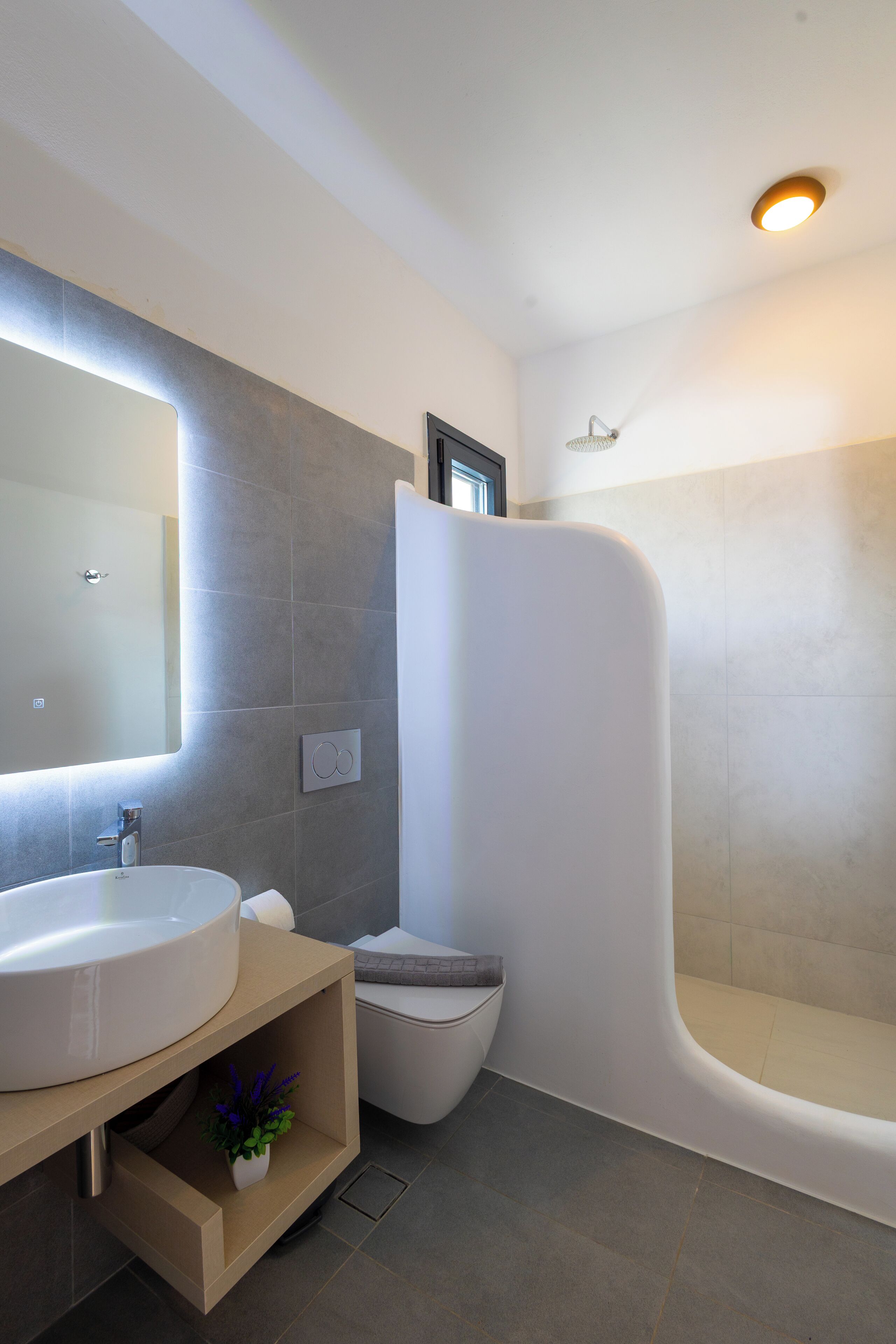 Un baño moderno con un lavamanos grande, inodoro y ducha curva.