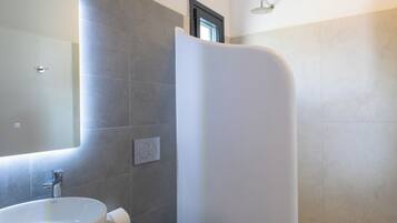 Un baño moderno con un lavamanos grande, inodoro y ducha curva.
