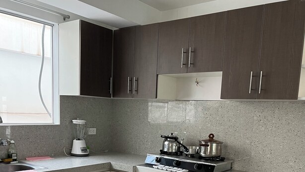 Una cocina moderna con encimeras de granito, armarios de madera oscura, una estufa a gas y un horno empotrado.