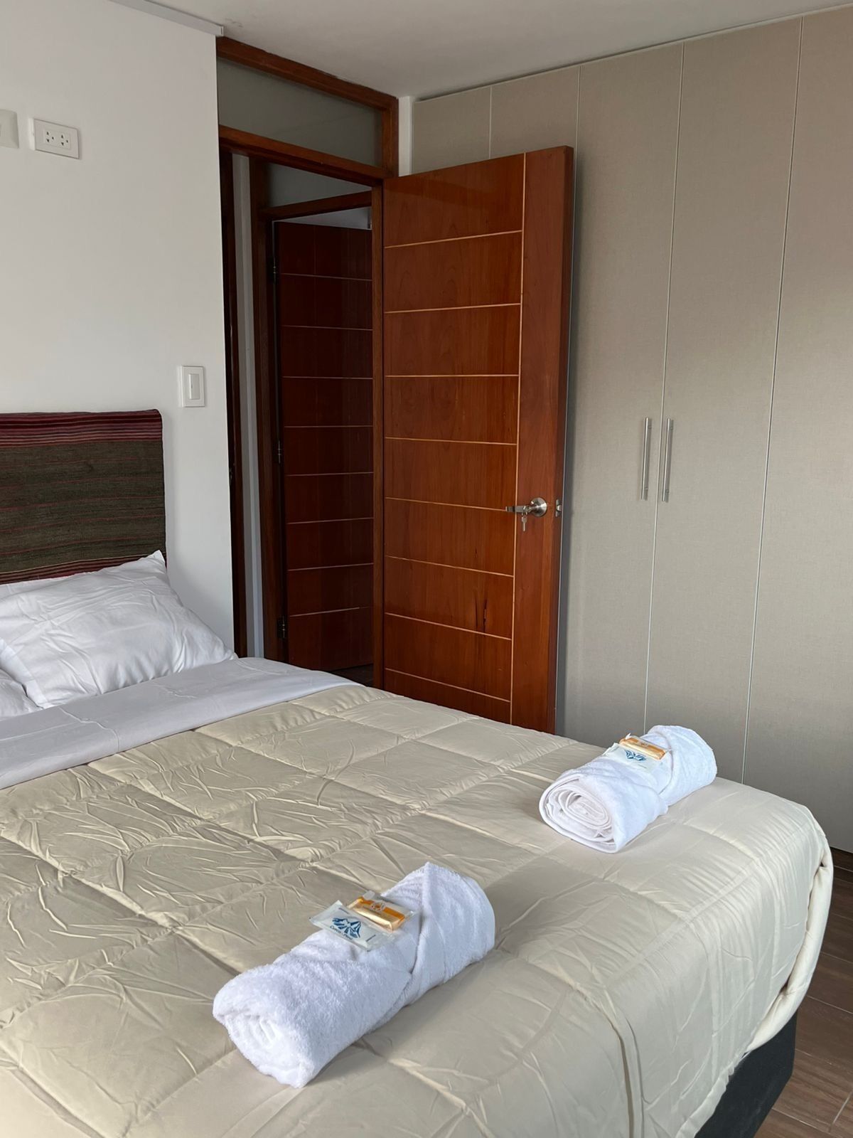 A hotel room with a bed, a wardrobe, and a door.