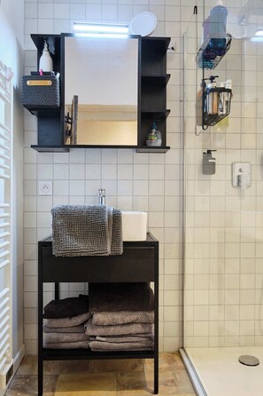A modern bathroom with a black vanity, a large mirror, and a shower area. - My family home (Vers-Pont-du-Gard)