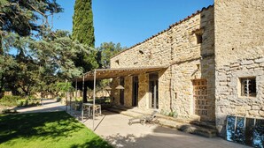 A stone building with a covered patio area, outdoor seating, and a stone wall. - My family home (Vers-Pont-du-Gard)