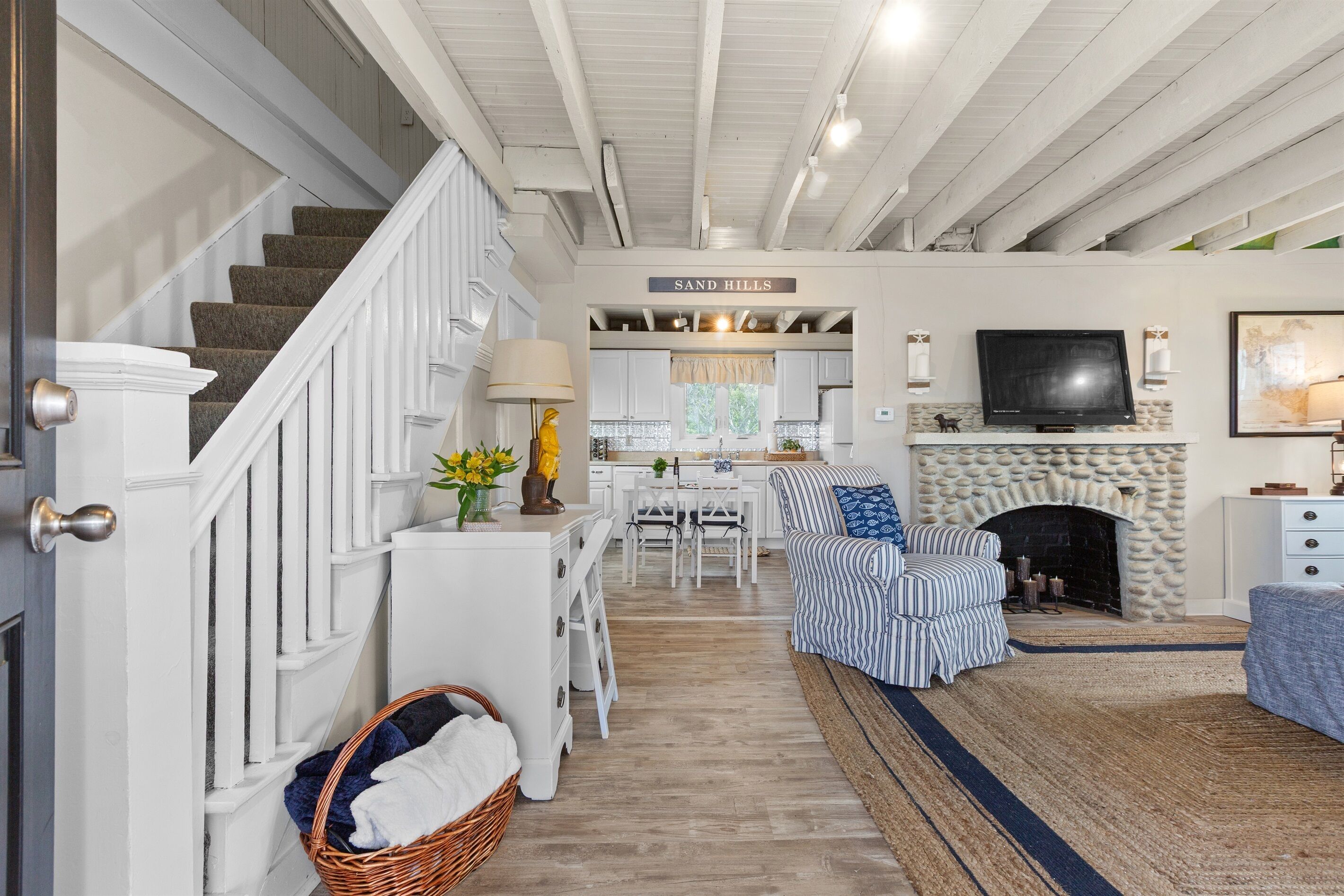 A spacious living area with a staircase, a fireplace, a television, and a dining area.