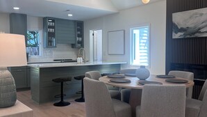 A modern kitchen with a central island, grey upholstered chairs around a wooden dining table, and a pendant light fixture above. - NEW 30+ day Modern Coastal 4bdrm 2 Masters (Mount Pleasant)
