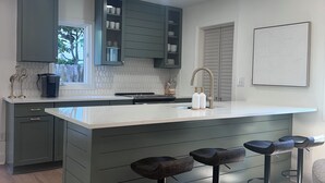 A modern kitchen with a central island, bar stools, and built-in cabinets. - NEW 30+ day Modern Coastal 4bdrm 2 Masters (Mount Pleasant)