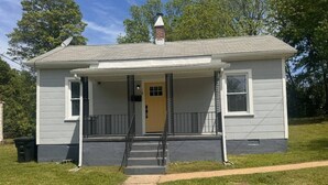 A single-story house with a front porch, a chimney, and a small front yard. - Charming Central Home-3bd/1bath (Danville)
