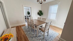 A dining area with a wooden table and chairs, a patterned rug, and a chandelier. - Charming Central Home-3bd/1bath (Danville)