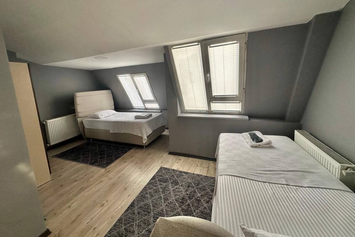 A bedroom with a bed, a sofa, a window, and a radiator.