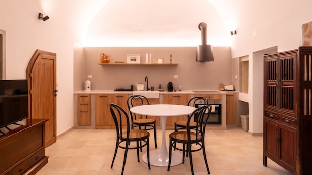 Une cuisine moderne avec une table de salle à manger ronde, des chaises et un téléviseur.