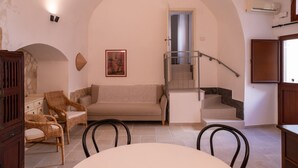 Un salon avec un canapé, des fauteuils, un escalier et une table à manger.