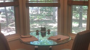 A round glass table with two chairs, a small decorative item, and folded towels on the table.