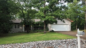 A residential house with a garage, surrounded by a well-maintained lawn and a rock border.