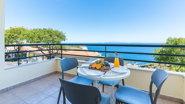 Un balcon avec une table préparée pour le petit-déjeuner, offrant une vue sur la côte.