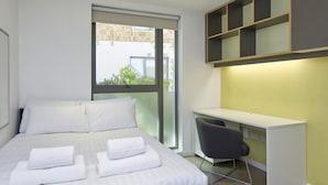 A modern hotel room with a large bed, a desk, and a chair. - Inviting Student Studio Minutes From City Centre (London)